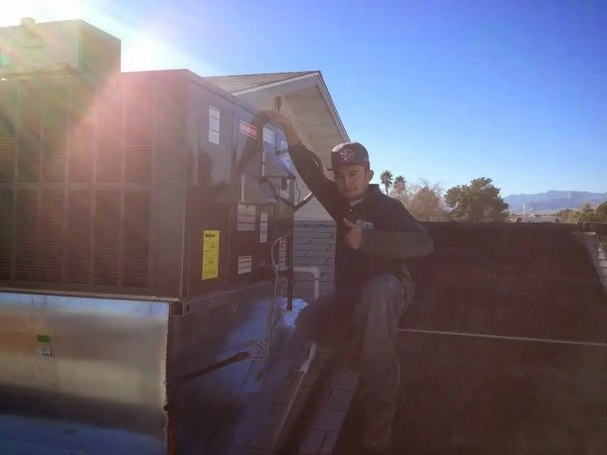 HVAC technician performing AC Tune-Up on a rooftop unit in Sanger