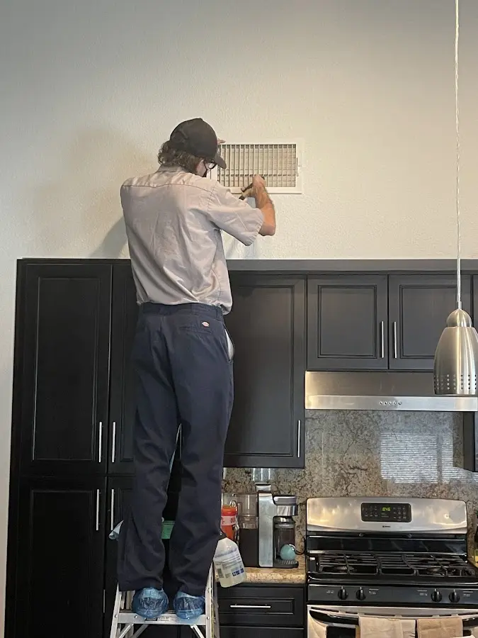 Technician inspecting an air vent during HVAC service in Sanger